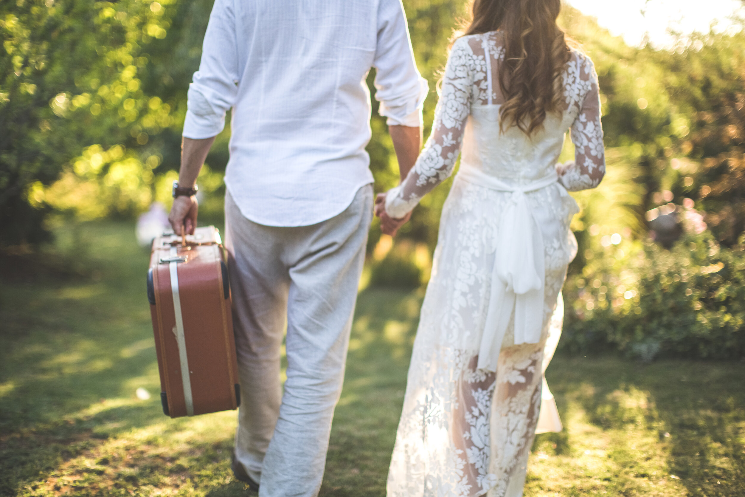 bride and groom holding hands carrying luggage.jpg