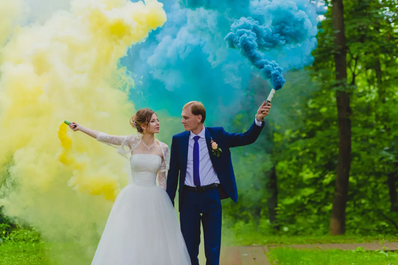bride and groom holding colorful smoke bombs for tie dye wedding