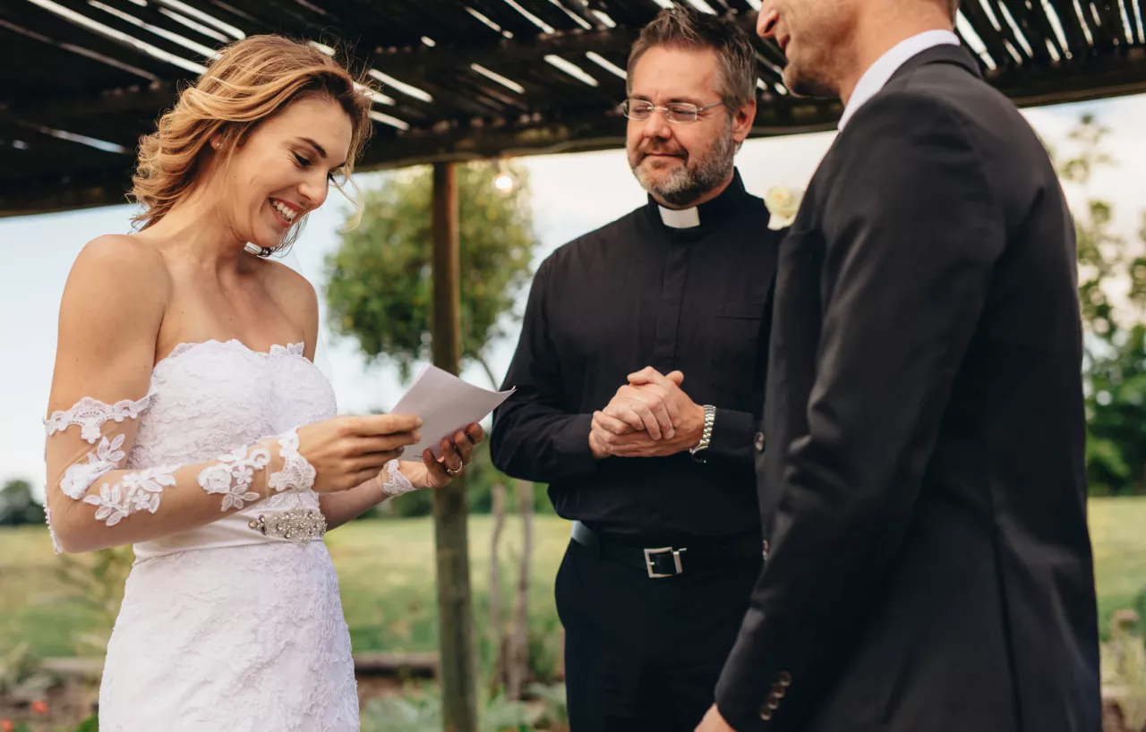 bride and groom reading vows at wedding ceremony with officiant standing by side