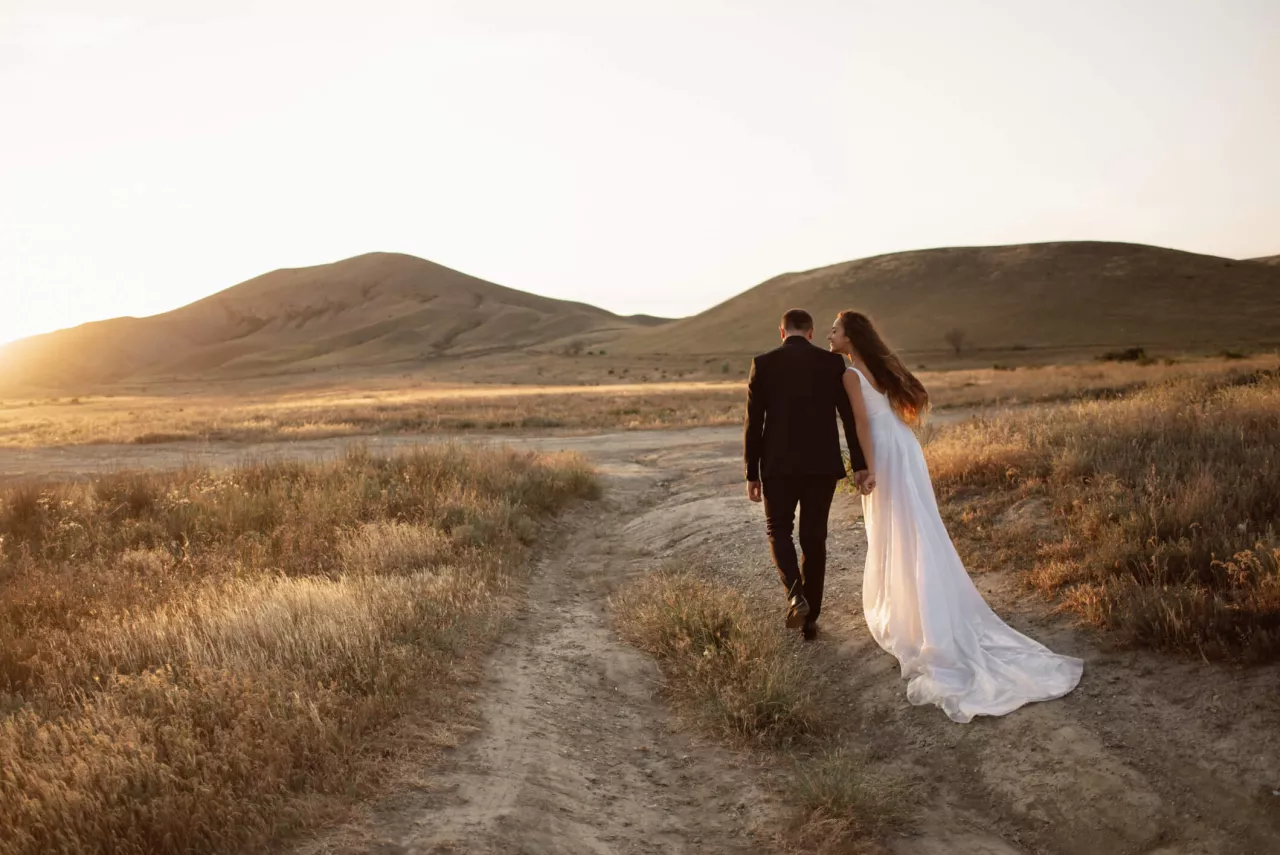 bride and groom walking into sunset of beautiful desert wedding