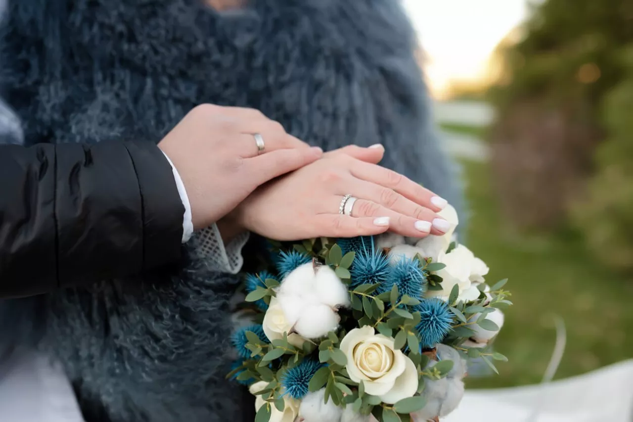 bride and groom holding hands and bouquet with teal wedding flowers