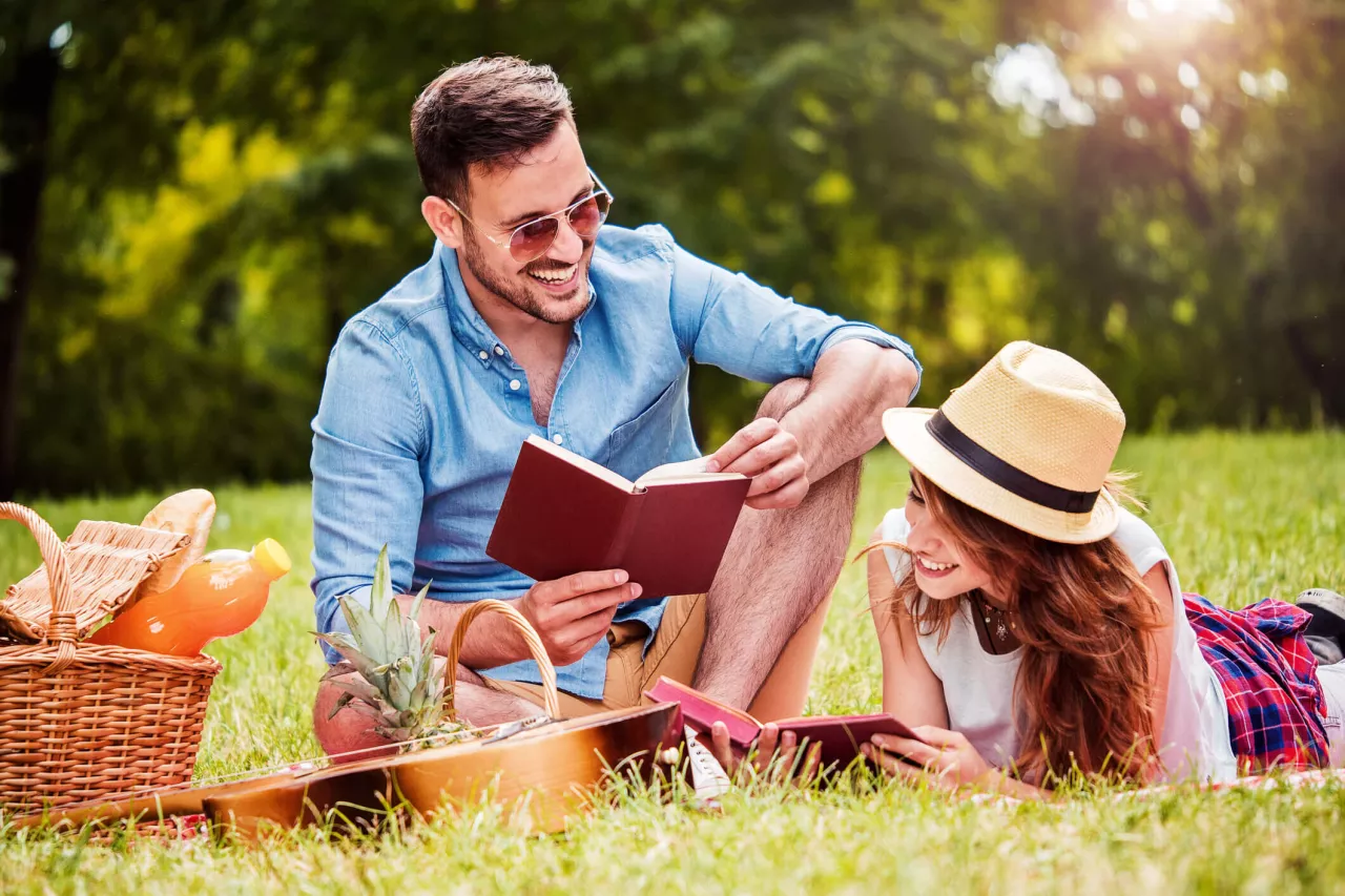 couple smiling reading books in park