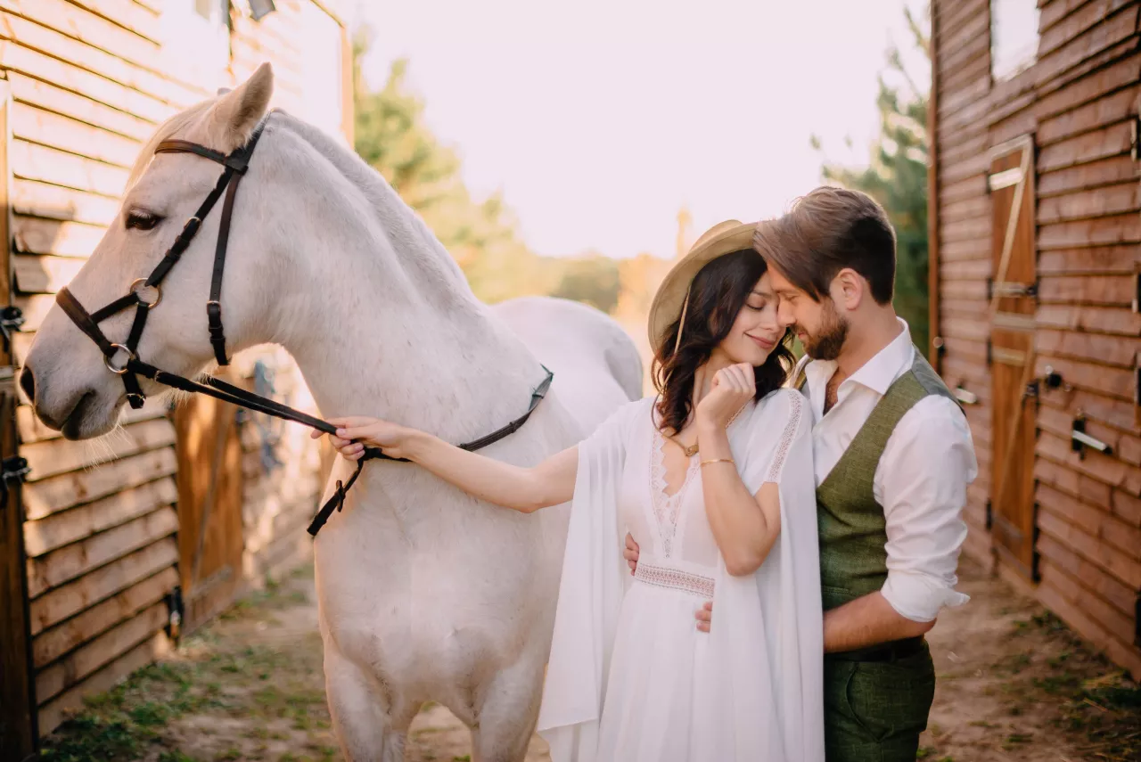 Bride and groom kissing in barn with horse