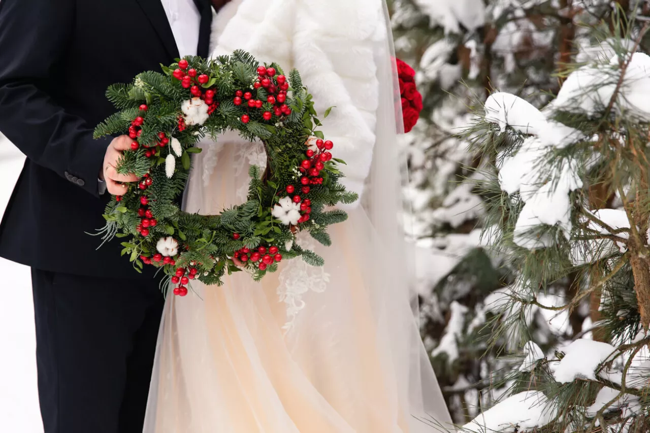 bride and groom holding wreath during christmas wedding