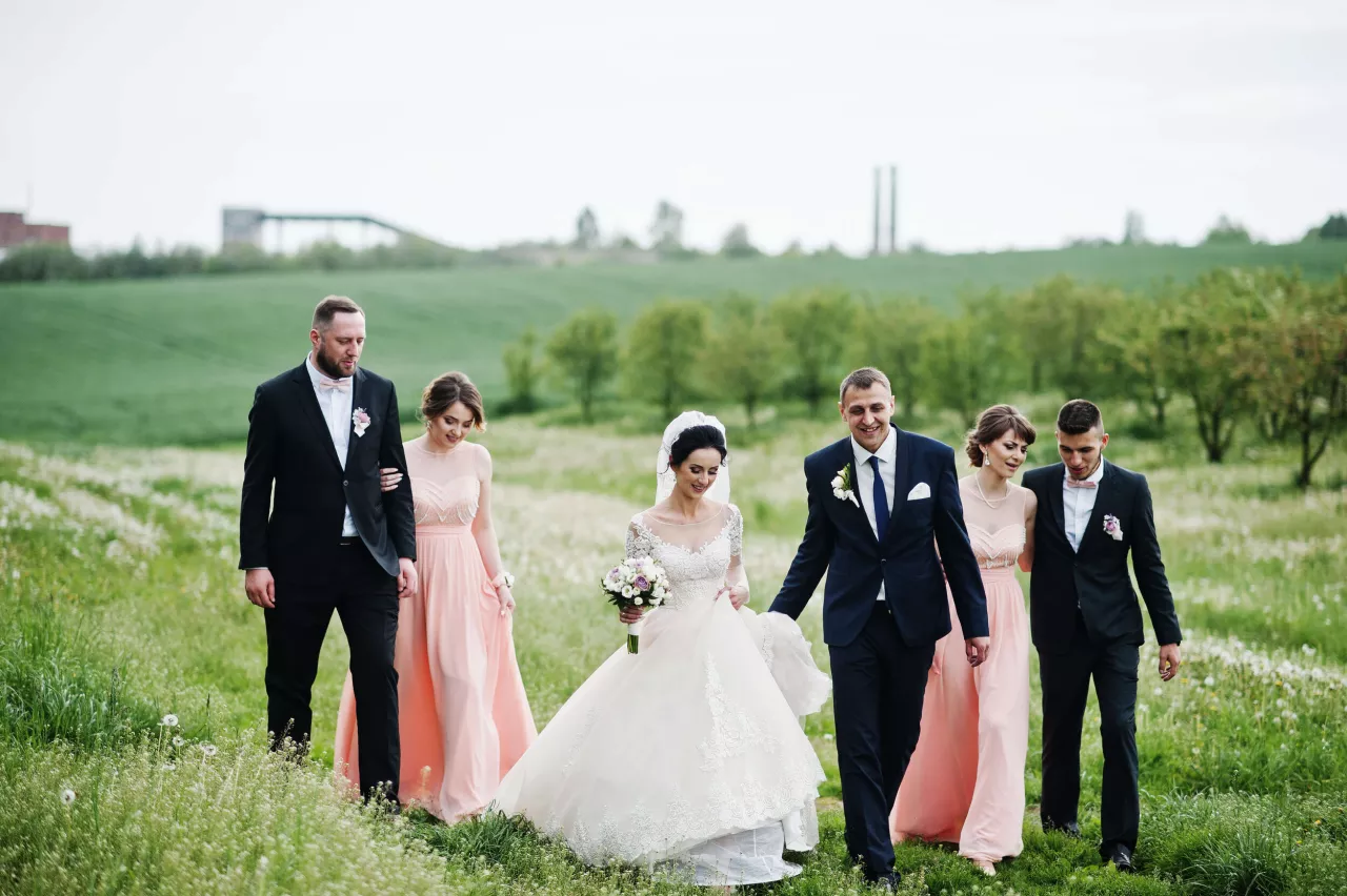 Bride groom and bridal party walking through field