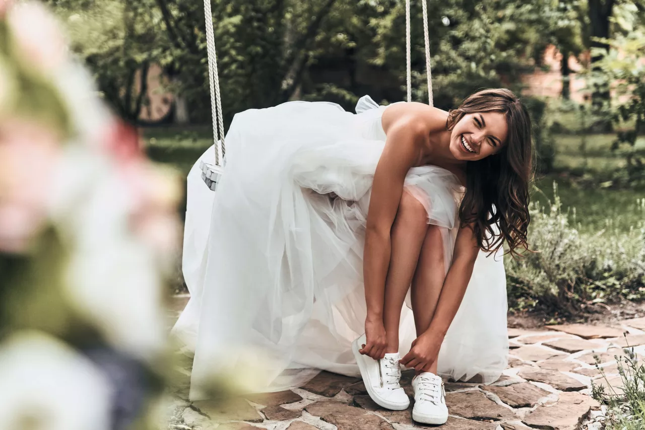 Bride smiling tying shoes on swing