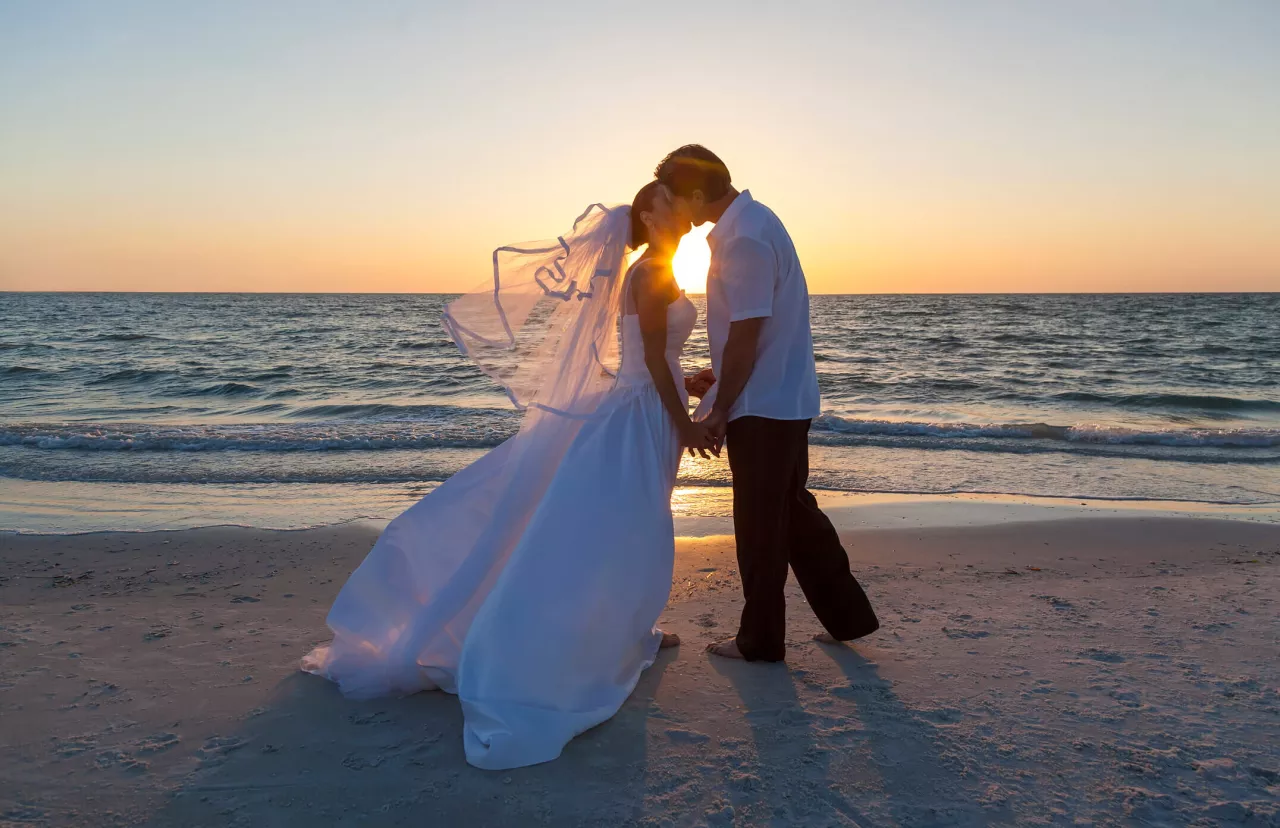 bride and groom kissing during beach wedding