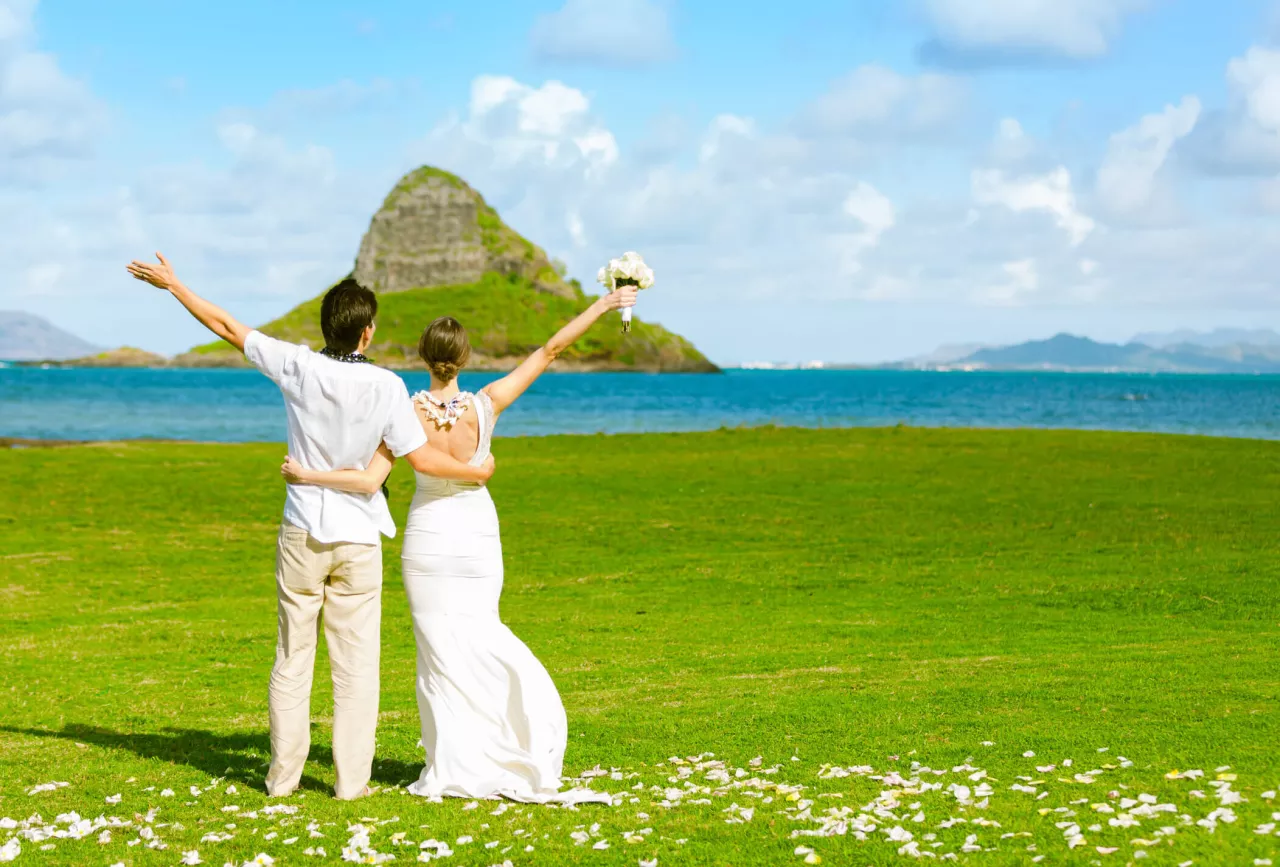 Just married couple throwing arms in air in Hawaii
