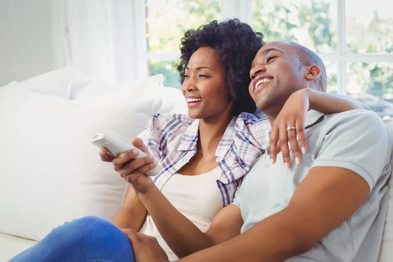 young engaged couple watching movie on couch 