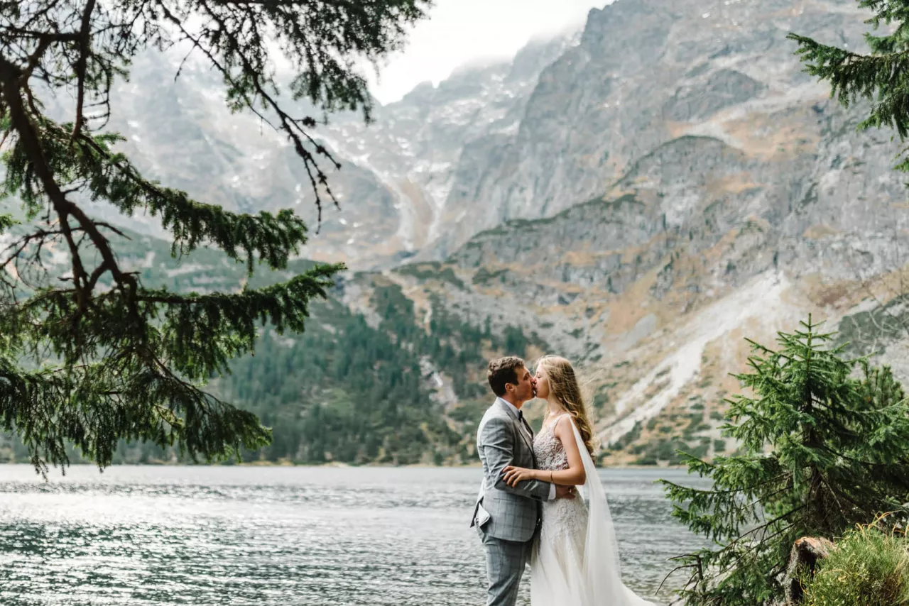 bride and groom kissing at beautiful outdoor wedding venues with lake and mountains