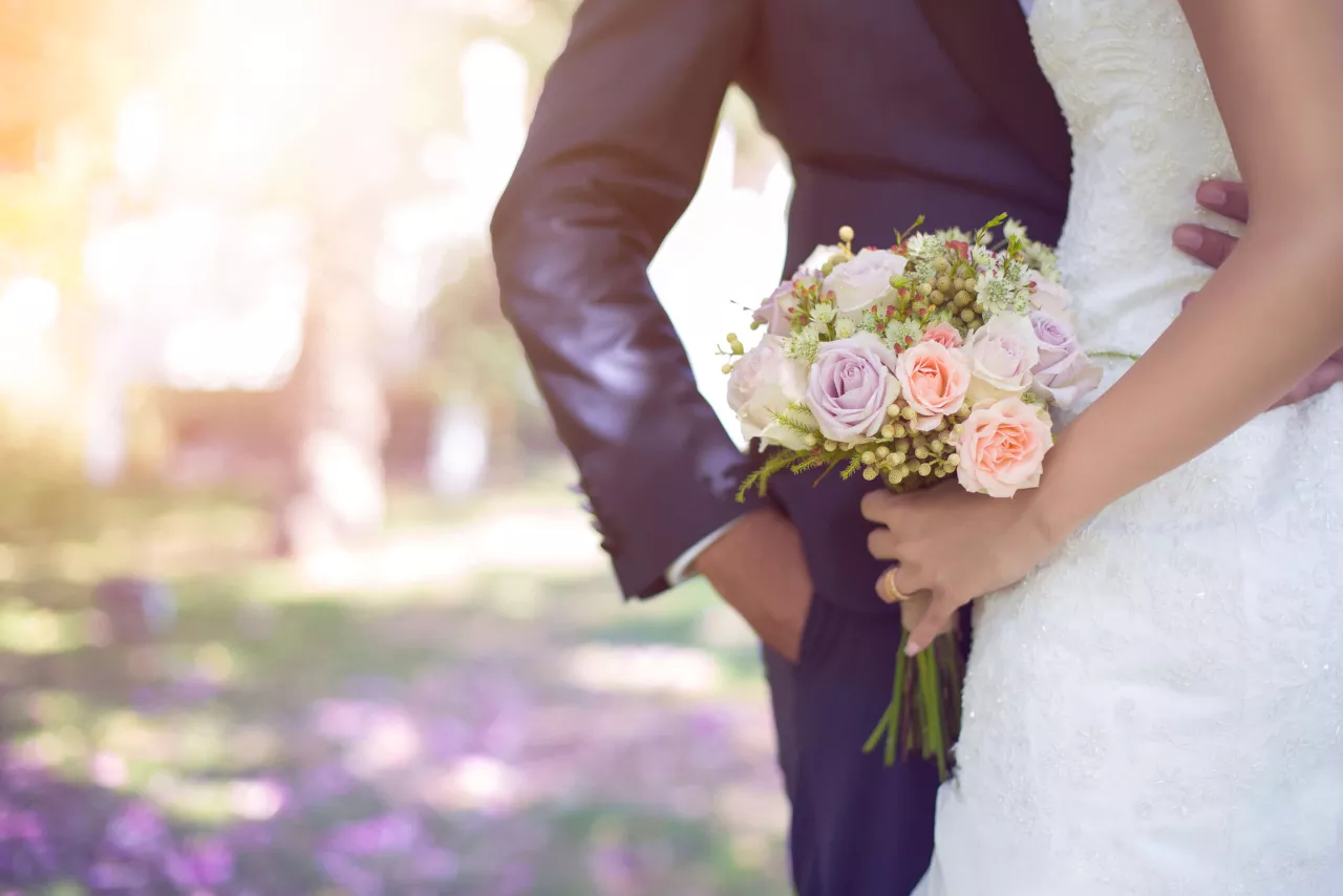 bride in white dress holding bouquet and hugging groom in blue suit
