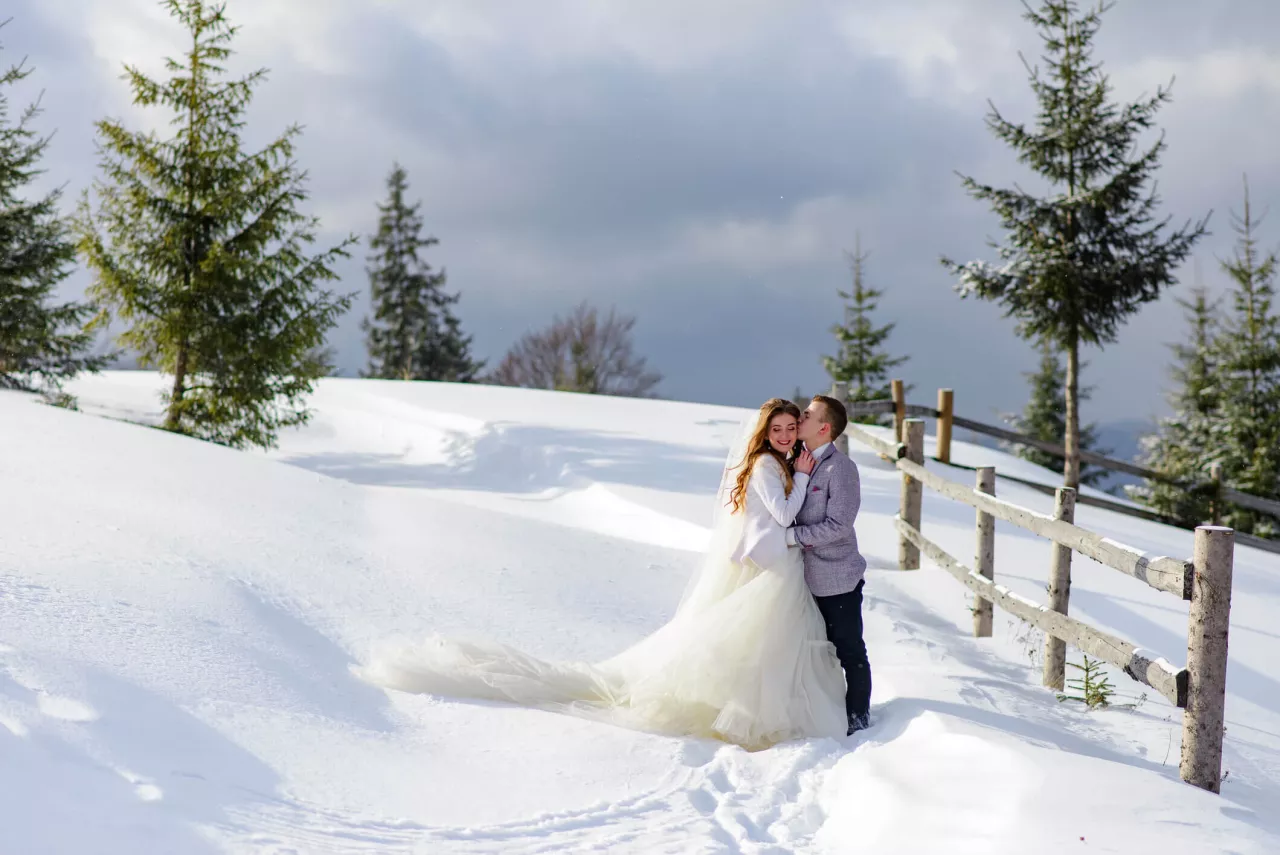 bride and groom kissing at beautiful winter wedding venue