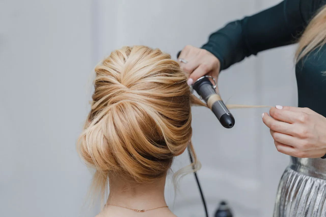 hairdresser creating beautiful hairstyle for bride