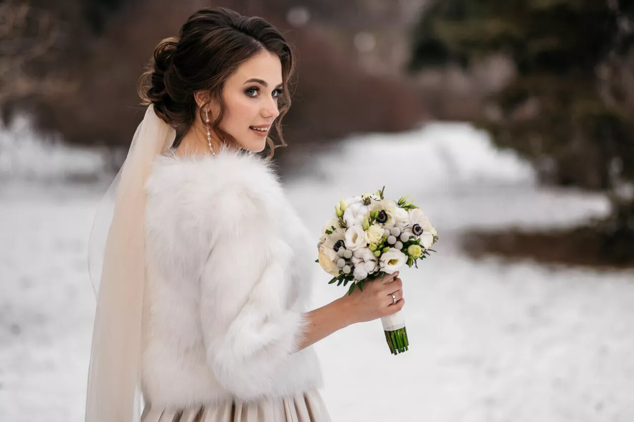 bride wearing fur wrap carrying bouquet