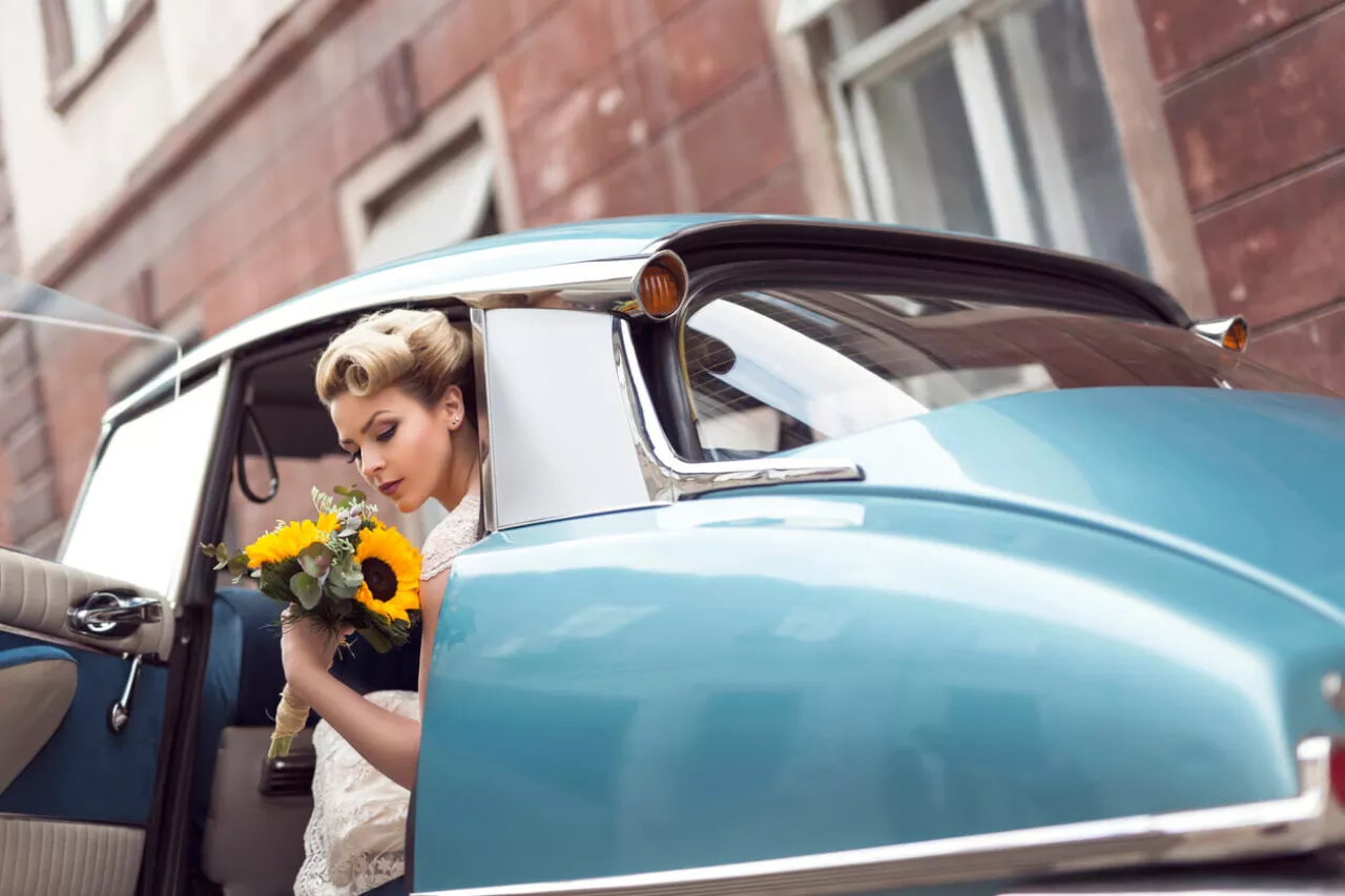 bride getting out of vintage car for 1960s-themed wedding