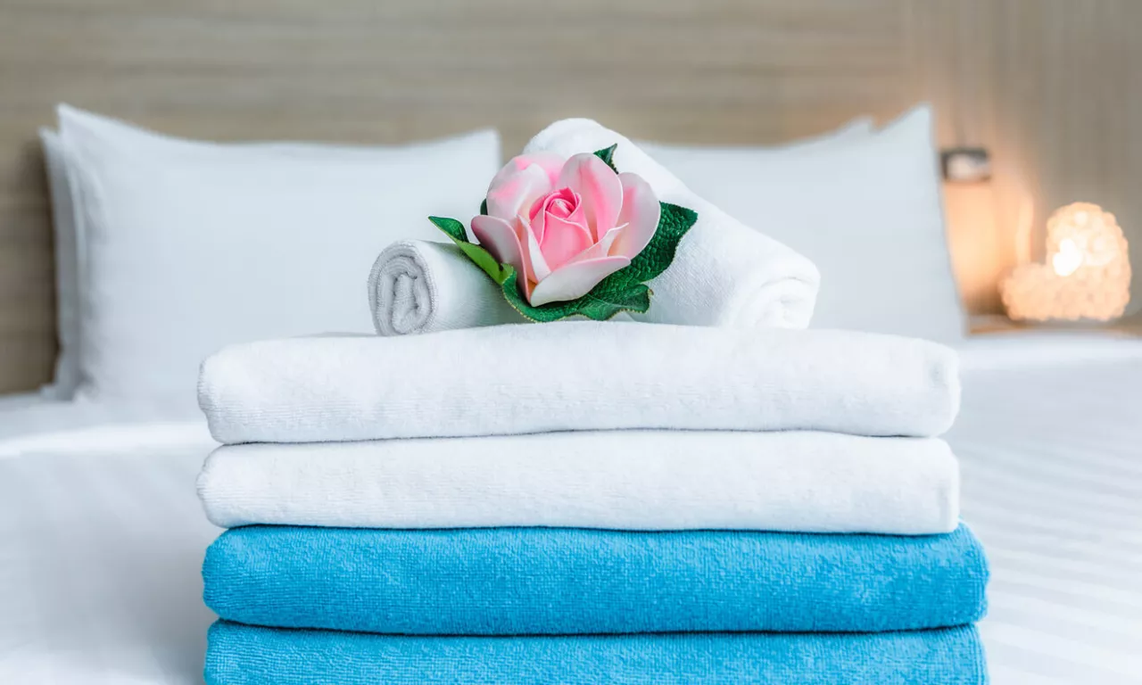 hotel room with towels and flower on bed to welcome wedding guests