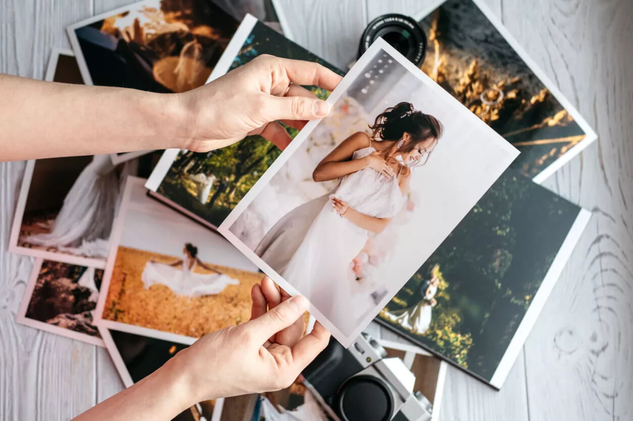 woman holding physical copies of wedding photos in her hands
