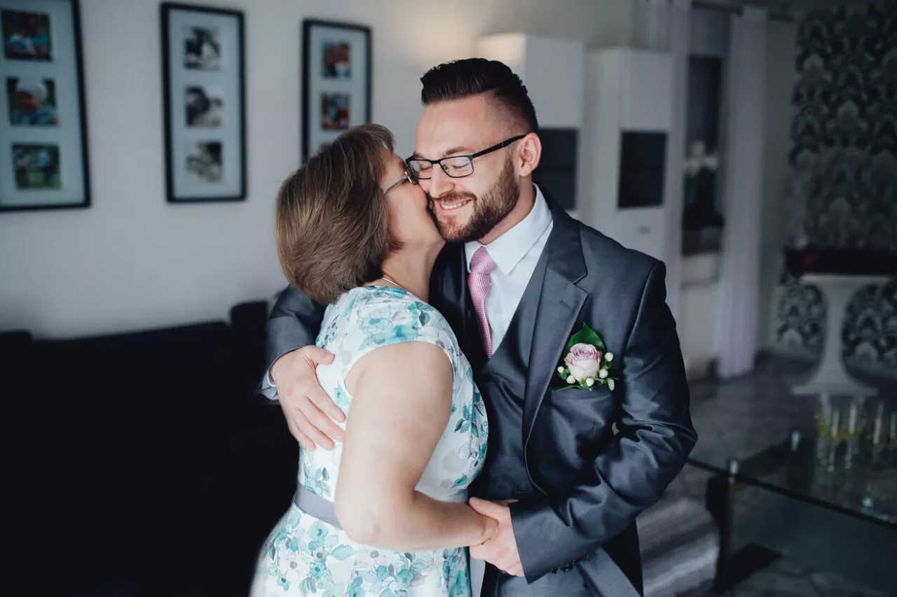 mother of the groom wearing floral dress hugging son on wedding day
