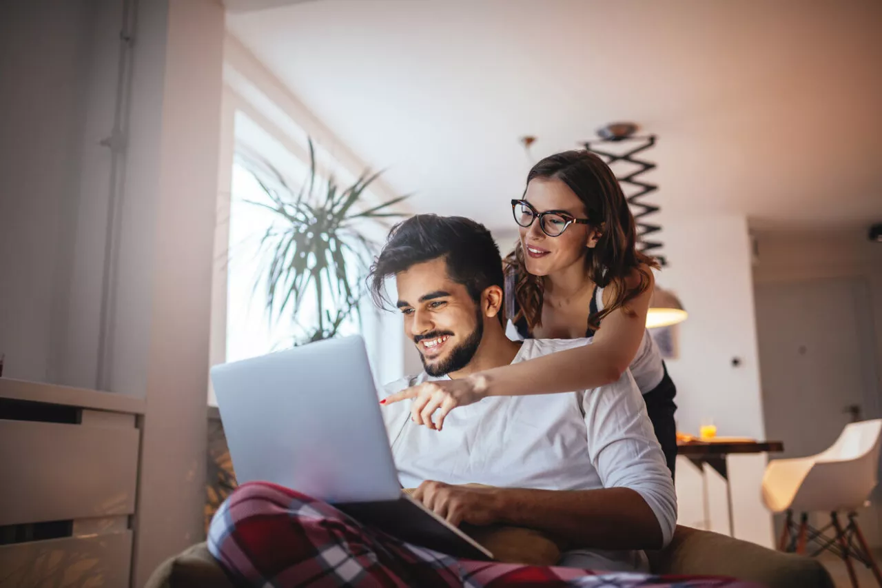 happy young couple smiling using laptop
