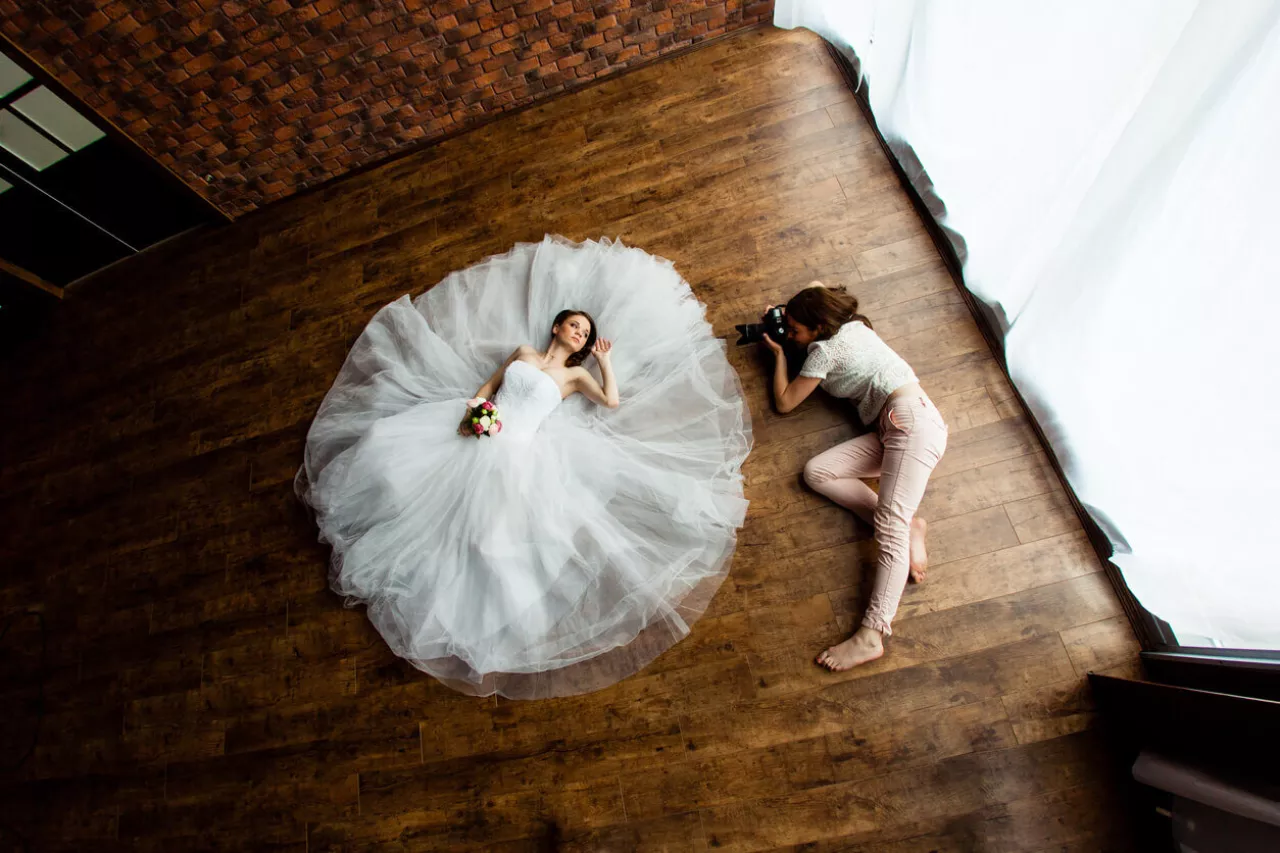 wedding photographer taking pictures of bride posing on ground in wedding dress