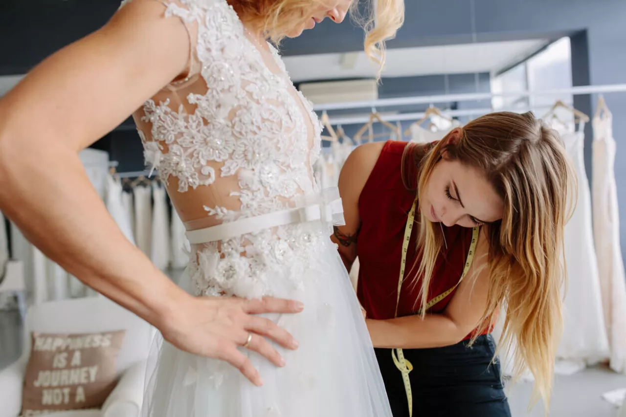 woman measuring bride for wedding dress alterations