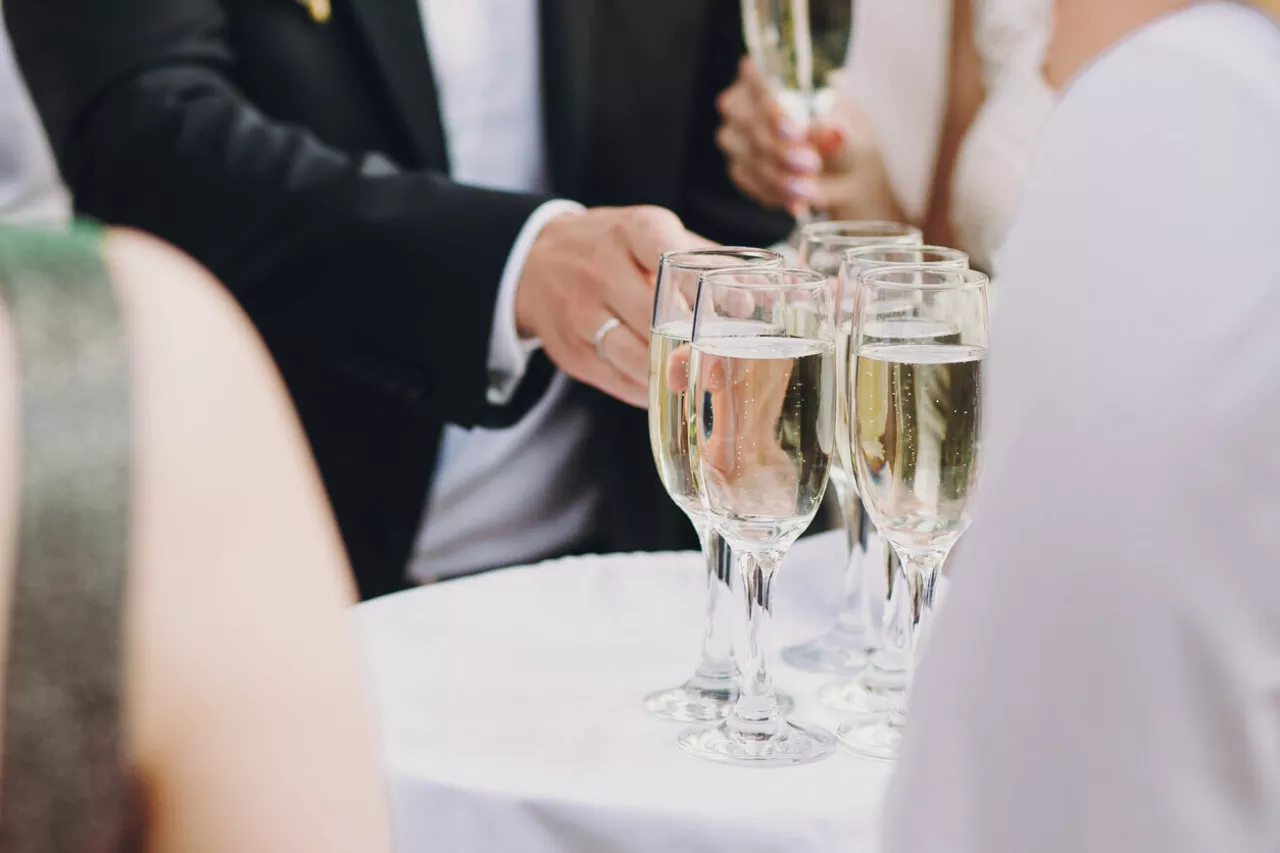 people reaching for champagne during wedding cocktail hour