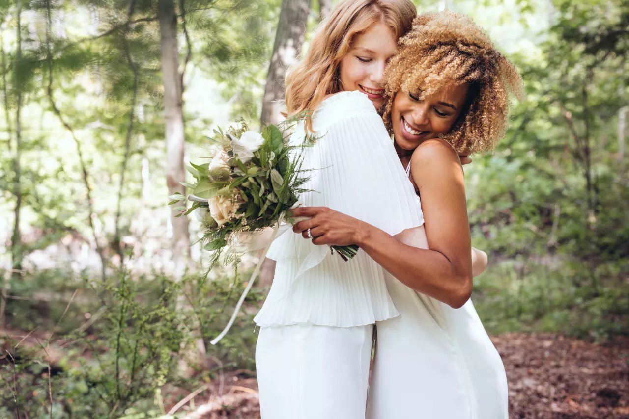 two women hugging with flowers on wedding day