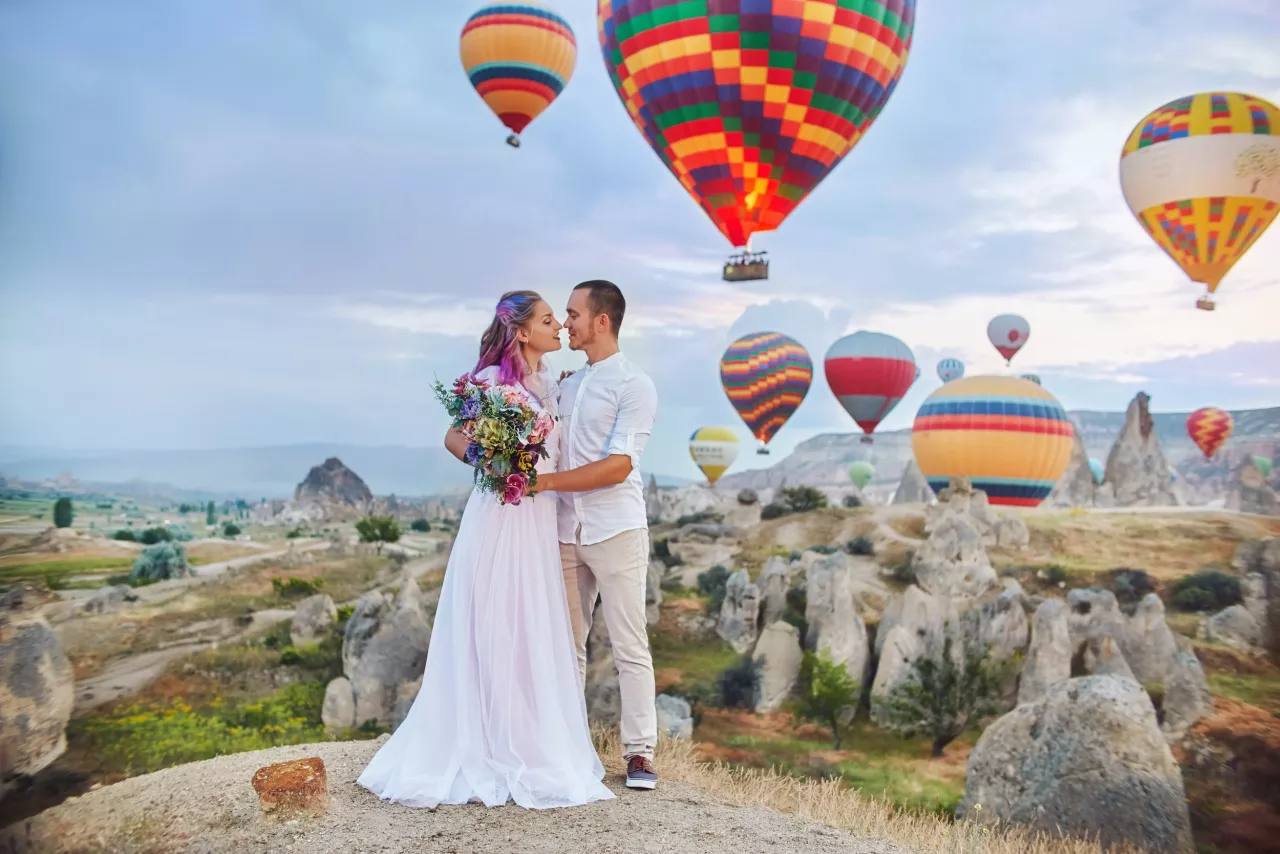 bride and groom kissing with hot air balloons in background