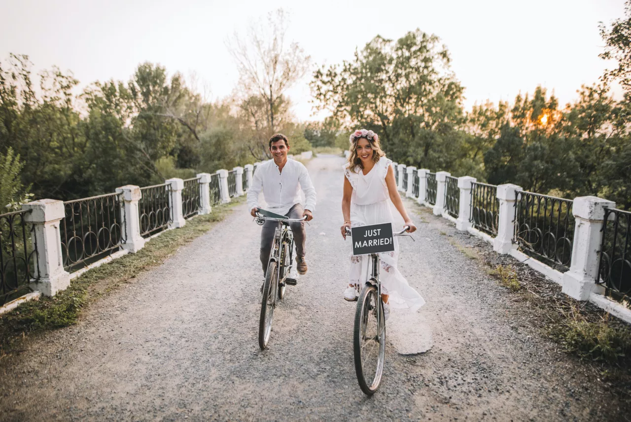 bride and groom on bikes with just married sign