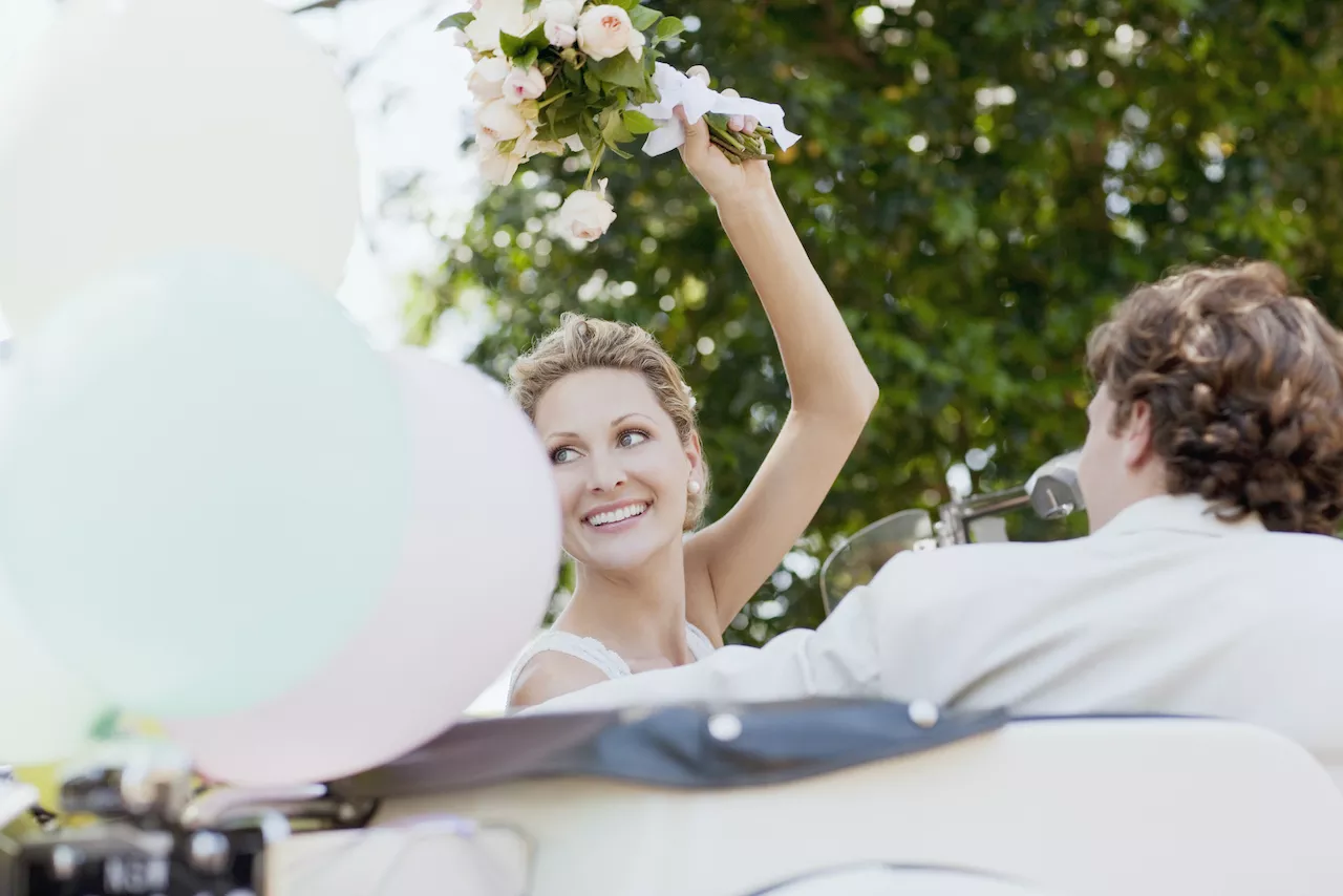 bride and groom smiling in car after wedding