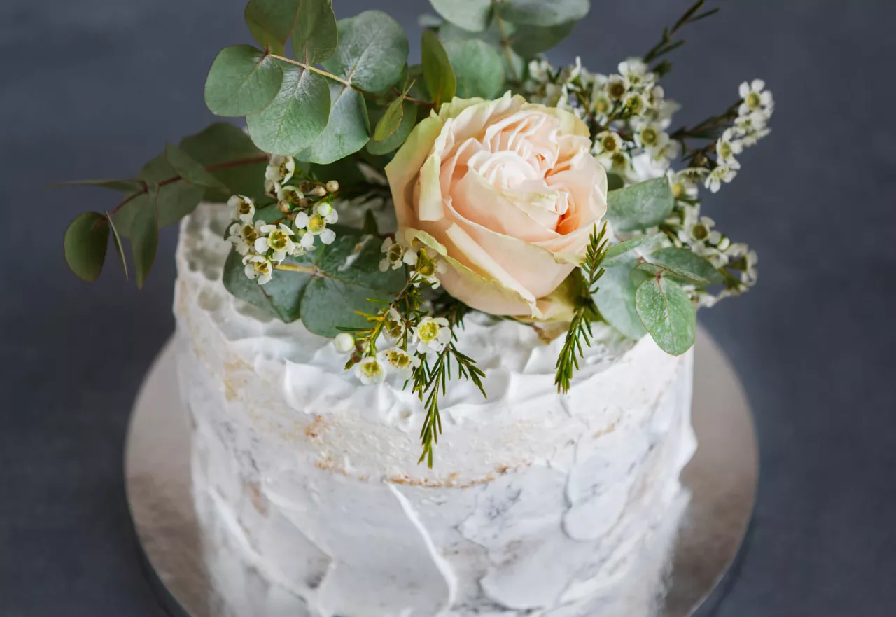 Wedding cake with white frosting and pink flower