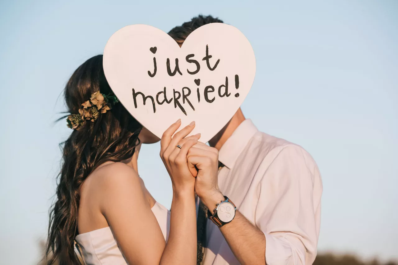 bride and groom kissing behind just married sign