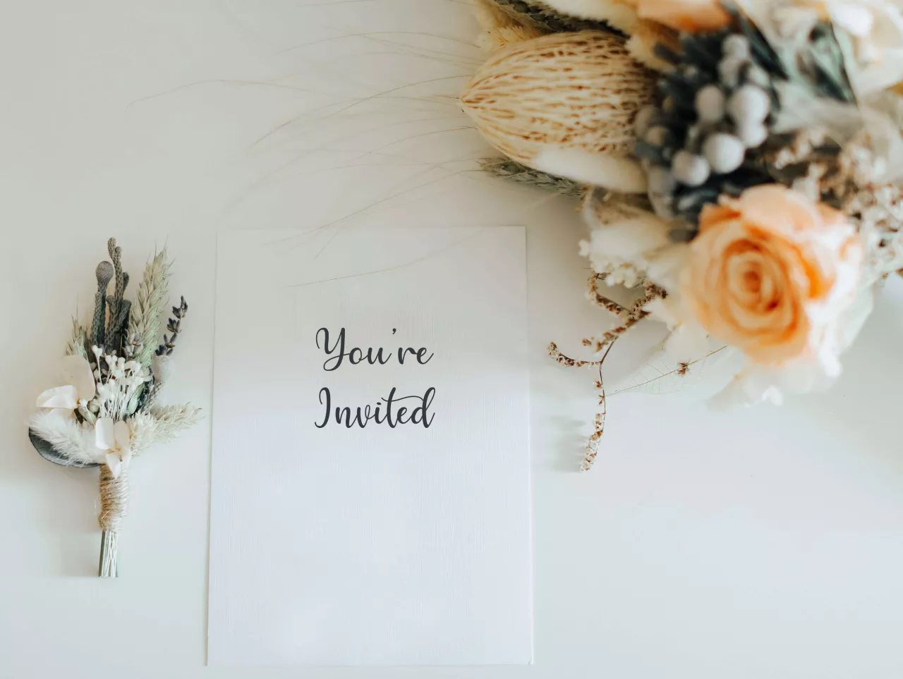 White wedding invitation with colorful flowers beside it