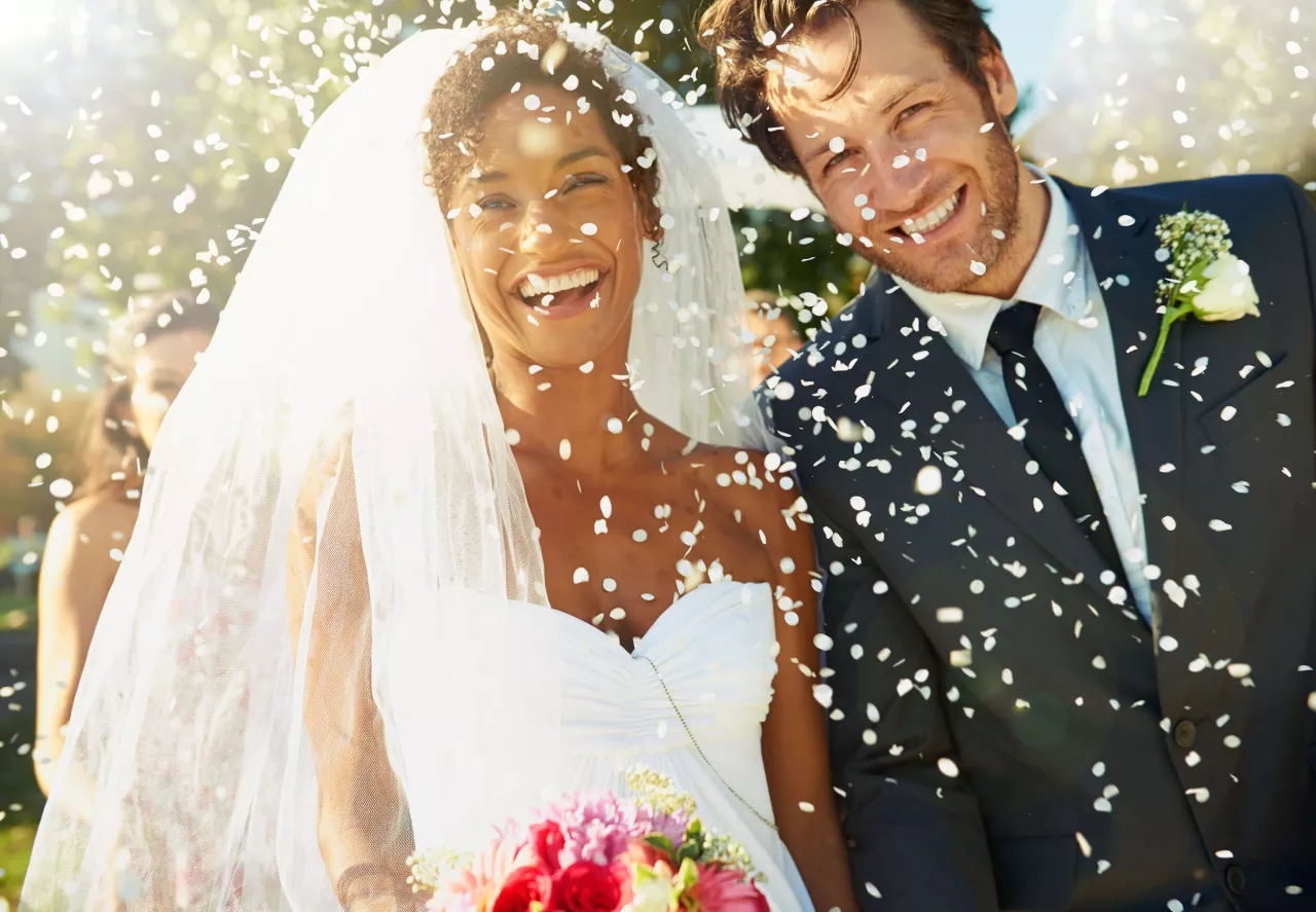 Bride and groom smiling with confetti falling
