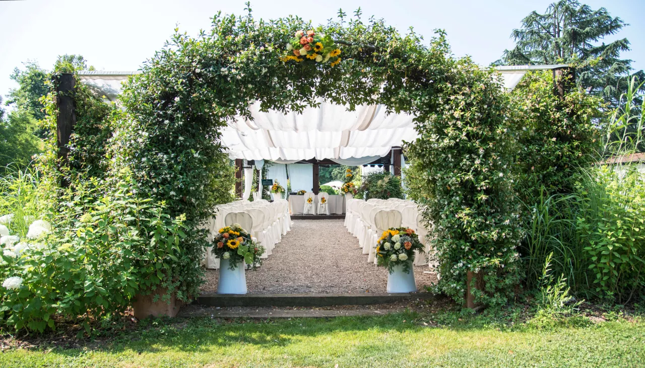 Outdoor wedding venue with greenery over aisle leading to altar