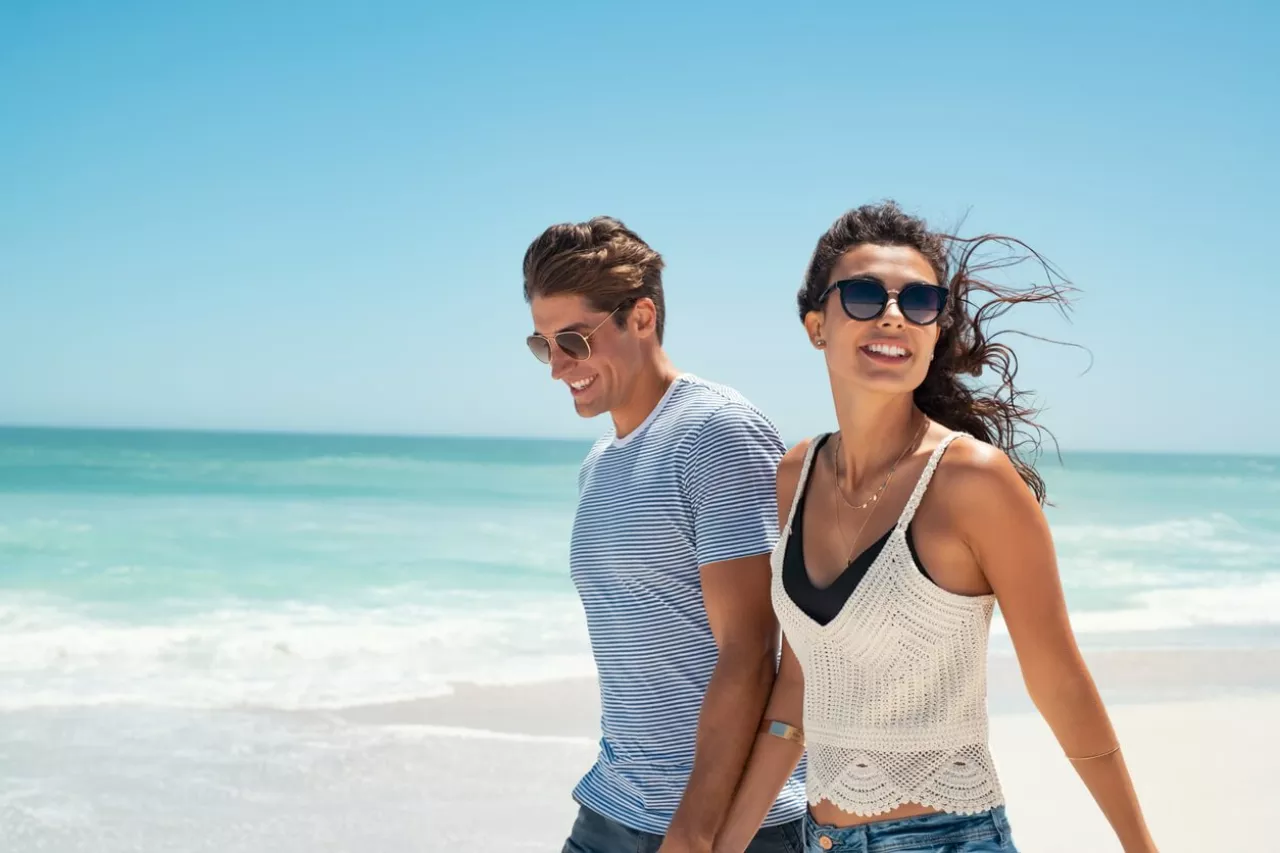 young engaged couple relaxing walking on beach
